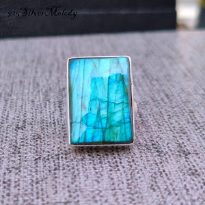 May include: A silver ring with a large, rectangular, iridescent blue labradorite gemstone.