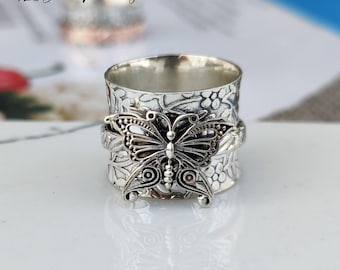 Könnte beinhalten: Ein silberner Drehring mit einem detaillierten Schmetterlingsdesign und floralen Mustern. Der Ring ist aus 925er Sterlingsilber gefertigt.