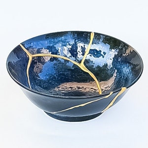May include: A dark blue ceramic bowl with gold cracks. The bowl is a traditional Japanese style.