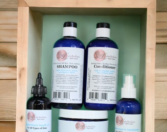May include: A set of hair care products in blue bottles with white labels. The products include shampoo, conditioner, hair oil, and hair butter. The labels feature the brand name "Labelledinie Hair-Care" and list the ingredients and benefits of each product. The products are arranged on a wooden shelf with a light green background.
