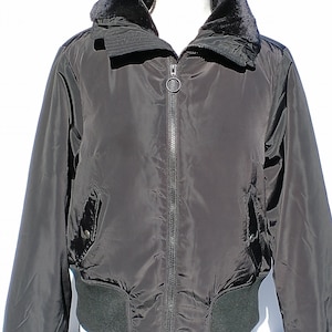 Puede incluir: Una chaqueta bomber negra con cuello de piel sint&eacute;tica y cierre de cremallera. La chaqueta tiene cintura y pu&ntilde;os de canal&eacute;.