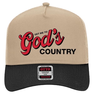 May include: A trucker hat with a tan front panel and a black brim. The hat features the text "Get Me To God's Country" in red and black lettering. The hat has a mesh back and an adjustable snap closure.