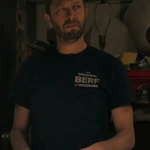 Peut inclure: Un homme portant un t-shirt bleu fonc&eacute; avec le texte "The Original Berf of Chicagoland" imprim&eacute; sur le devant. Il tient une cigarette dans sa main droite.