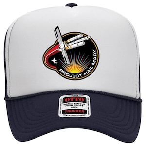 May include: A white and navy blue trucker hat with a graphic featuring a spaceship design and the text "PROJECT HAIL MARY". The hat has a foam front and a snap closure. The hat is made of a soft and comfortable material.