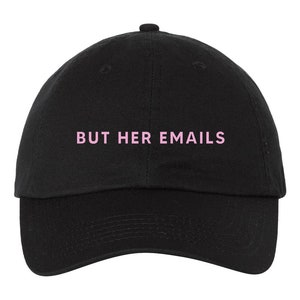 May include: A black baseball cap with the text "BUT HER EMAILS" embroidered in pink.