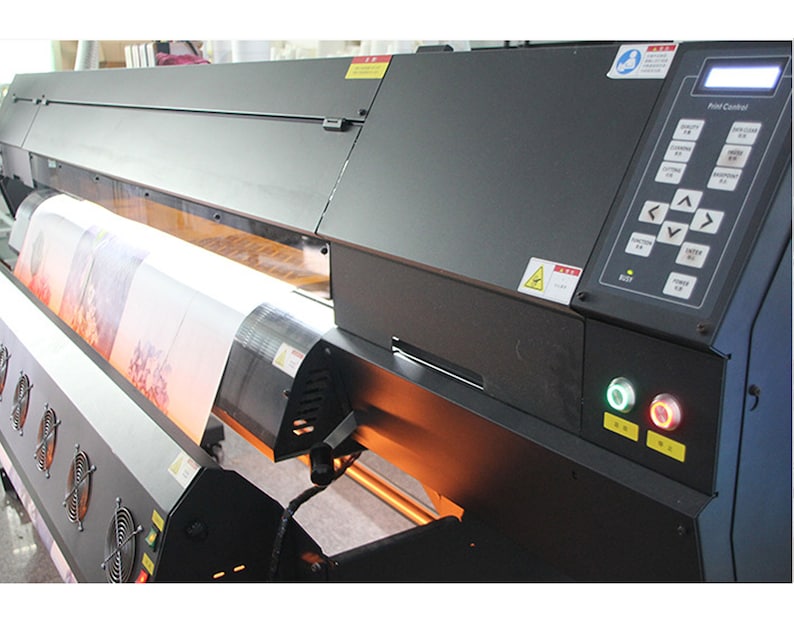May include: A large format printer with a roll of canvas being fed through the machine. The printer has a control panel with buttons and a display screen that reads "Print Control".