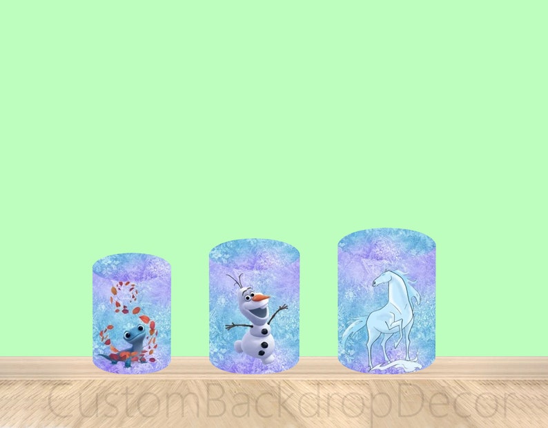 Puede incluir: Tres contenedores cil&iacute;ndricos con un dise&ntilde;o azul y morado escarchado. Cada contenedor presenta un personaje diferente de la pel&iacute;cula Frozen II: un lagarto azul, Olaf el mu&ntilde;eco de nieve y un caballo blanco.