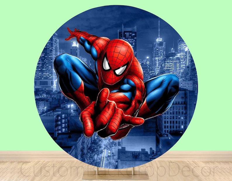 May include: A round backdrop featuring a red and blue superhero character with a spider design. The character is posed in a dynamic action pose against a cityscape background.