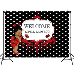 May include: Black and white polka dot backdrop with a red ladybug chandelier and a little girl wearing a red ladybug costume. The backdrop says "Welcome Little Ladybug".