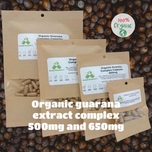 May include: Four brown paper bags with white labels containing organic guarana extract complex capsules. The labels state "100% Organic" and "Organic Guarana Complex Capsules 500mg". The bags are arranged in a pyramid shape on a background of brown nuts.