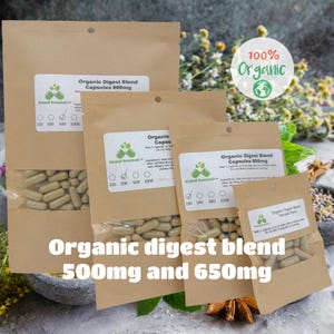 May include: Three brown paper bags with white labels containing organic digest blend capsules in various sizes. The labels state "Organic Digest Blend Capsules 500mg" and "Organic Digest Blend Sample Pack". The bags are on a table with a mortar and pestle, herbs, and spices.
