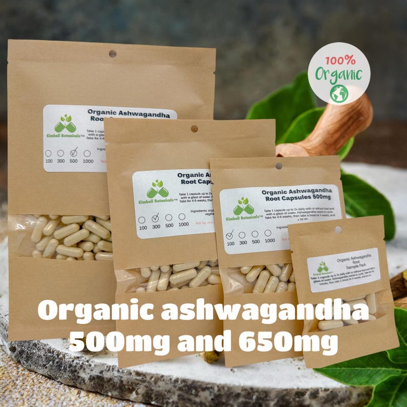 May include: Four brown paper bags with white labels containing organic ashwagandha root capsules. The bags are labeled with the text "Organic Ashwagandha Root Capsules" and the dosage in milligrams. The bags are arranged in a pyramid shape, with the largest bag at the bottom and the smallest bag at the top. The bags are sitting on a wooden surface.