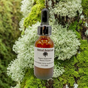 May include: A brown glass bottle with a black dropper, labeled "Kimball Botanicals." The label reads "Organic Usnea Lichen Glycerin Tincture." The bottle is set against a backdrop of green and white moss.