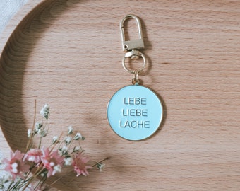 Schlüsselanhänger "Lebe Liebe Lache" aus Metall in türkis und gold