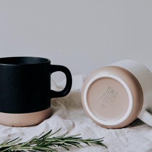 Zwei gravierte Keramiktassen im modernen Steingut Design und unglasiertem Bodendesign in Natur, Die Gravur auf der Frontseite ist frei gestaltbar und kann für Rechtshänder oder Linkshänder ausgewählt werden.