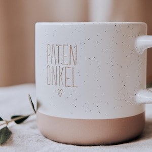 Gravierte Keramiktasse mit modernem Steingutdesign  weißer matter Lasur und kleinen sprenkeln der Oberfläche und unglasiertem Bodendesign in Natur. Im Detailbild werden die ungleichmäßigen Sprenkel der Tasse sichtbar.