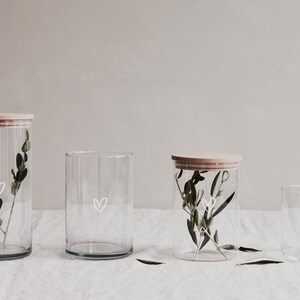 Alle Größenvarianten des Vorratsglases von 1200ml, 880ml, 700ml und 530ml. Jedes der Gläser hat ein weißes Herz auf dem Glas und einem Deckel aus Buchenholz.