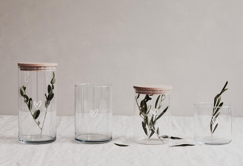 Alle Größenvarianten des Vorratsglases von 1200ml, 880ml, 700ml und 530ml. Jedes der Gläser hat ein weißes Herz auf dem Glas und einem Deckel aus Buchenholz.