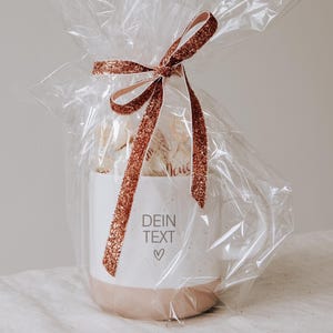Gravierte Keramiktasse eingepackt als Geschenk mit Folie und gefüllt mit Pralinen. Geschenk für den Lieblingsmenschen