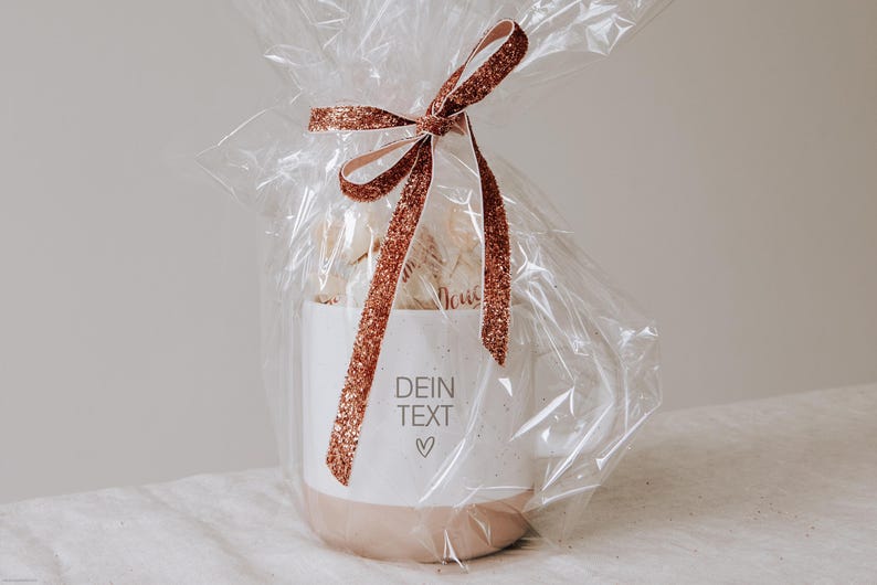 Gravierte Keramiktasse eingepackt als Geschenk mit Folie und gefüllt mit Pralinen. Geschenk für den Lieblingsmenschen