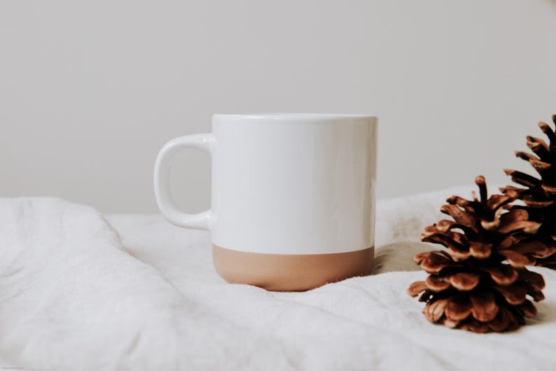 Steinguttasse gin Nahaufnahme mit glanzweiß in einer gemütliche Atmosphäre  – Tasse mit glänzender Lasur der Oberfläche und unglasiertem Bodendesign in Natur, individuell anpassbar nach euren wünschen.