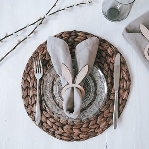Elegantes Ostertisch-Set mit handgefertigtem, geflochtenem Platzdeckchen, verziert mit stilvollem Geschirr und einem charmanten Hasen-Serviettenring. Perfekt für eine festliche Frühlingsstimmung. Hochwertige Materialien und liebevolle Details machen jede Mahlzeit zu einem besonderen Erlebnis. Ideal für stilvolle Osterdekoration und unvergessliche Familienmomente.