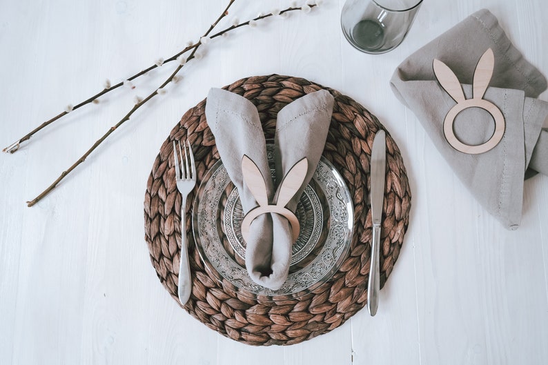 Elegantes Ostertisch-Set mit handgefertigtem, geflochtenem Platzdeckchen, verziert mit stilvollem Geschirr und einem charmanten Hasen-Serviettenring. Perfekt für eine festliche Frühlingsstimmung. Hochwertige Materialien und liebevolle Details machen jede Mahlzeit zu einem besonderen Erlebnis. Ideal für stilvolle Osterdekoration und unvergessliche Familienmomente.