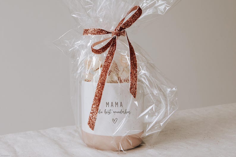 Gravierte Keramiktasse eingepackt als Geschenk mit Folie und gefüllt mit Pralinen. Geschenk für den Lieblingsmenschen. Mama Papa du bist wunderbar
