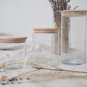 Elegante Vorratsgläser mit Holzdeckel, perfekt zur stilvollen Aufbewahrung in Ihrer Küche. Diese hochwertigen Glasbehälter halten Lebensmittel frisch und verleihen Ihrem Zuhause eine natürliche, warme Atmosphäre. Ideal für Zucker, Mehl oder Kaffee. Erleben Sie die perfekte Kombination aus Funktionalität und ästhetischem Design. Ein Muss für jeden, der Wert auf Qualität legt.