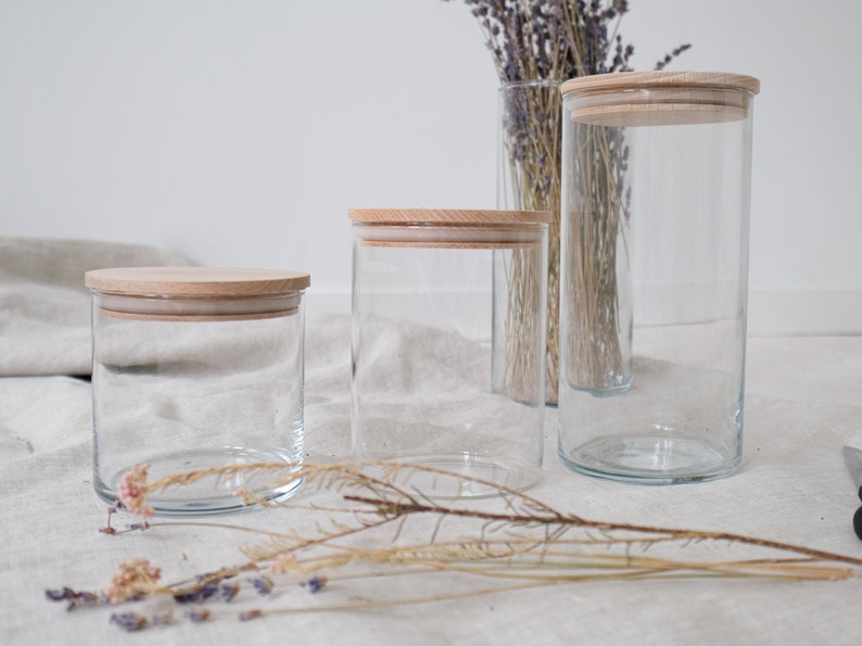 Elegante Vorratsgläser mit Holzdeckel, perfekt zur stilvollen Aufbewahrung in Ihrer Küche. Diese hochwertigen Glasbehälter halten Lebensmittel frisch und verleihen Ihrem Zuhause eine natürliche, warme Atmosphäre. Ideal für Zucker, Mehl oder Kaffee. Erleben Sie die perfekte Kombination aus Funktionalität und ästhetischem Design. Ein Muss für jeden, der Wert auf Qualität legt.