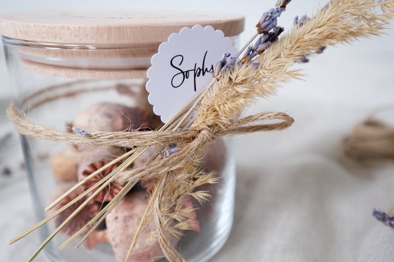 Dekoriertes Vorratsglas mit graviertem Holzdeckel und Trockenblumen als Deko. Kann Spuren von Glück enthalten.