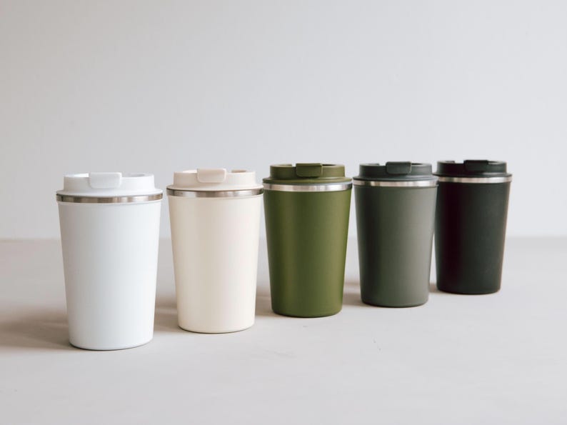 Stilvolle Thermobecher in beruhigenden Naturtönen stehen in einer harmonischen Reihe und laden zu entspannten Momenten ein. Diese hochwertigen Becher aus Edelstahl sind perfekt für Kaffee, Tee oder kalte Getränke und halten Ihre Lieblingsgetränke lange auf Temperatur. Ideal für unterwegs oder im Büro – erleben Sie nachhaltigen Genuss mit Stil und Funktionalität.