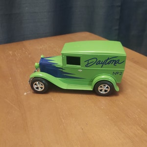 Puede incluir: Modelo de juguete verde de un cami&oacute;n de reparto vintage con detalles azules y la palabra "Daytona" escrita en el lateral. El cami&oacute;n tiene una parrilla negra y ruedas negras con tapacubos plateados. El cami&oacute;n est&aacute; etiquetado como "No. 2".