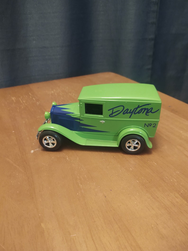 Puede incluir: Modelo de juguete verde de un cami&oacute;n de reparto vintage con detalles azules y la palabra "Daytona" escrita en el lateral. El cami&oacute;n tiene una parrilla negra y ruedas negras con tapacubos plateados. El cami&oacute;n est&aacute; etiquetado como "No. 2".