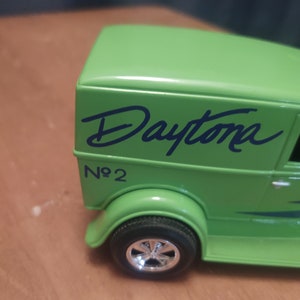 Puede incluir: Cami&oacute;n de reparto de juguete verde con la palabra "Daytona" escrita en negro en el lateral. El cami&oacute;n tiene una franja negra y el n&uacute;mero "No. 2" escrito en el lateral.