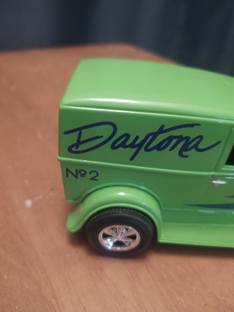Puede incluir: Cami&oacute;n de reparto de juguete verde con la palabra "Daytona" escrita en negro en el lateral. El cami&oacute;n tiene una franja negra y el n&uacute;mero "No. 2" escrito en el lateral.