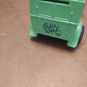 Puede incluir: Modelo de coche verde con una caja blanca en la parte trasera. El coche tiene las palabras "Bike Week '94" escritas en la parte trasera.