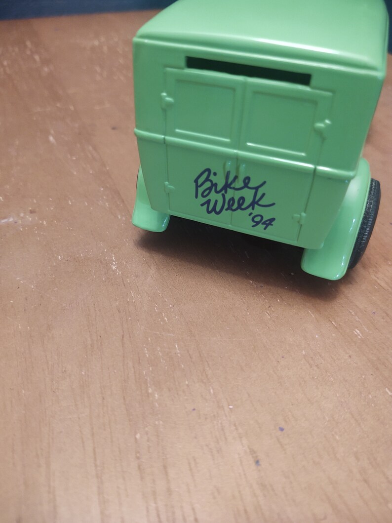 Puede incluir: Modelo de coche verde con una caja blanca en la parte trasera. El coche tiene las palabras "Bike Week '94" escritas en la parte trasera.
