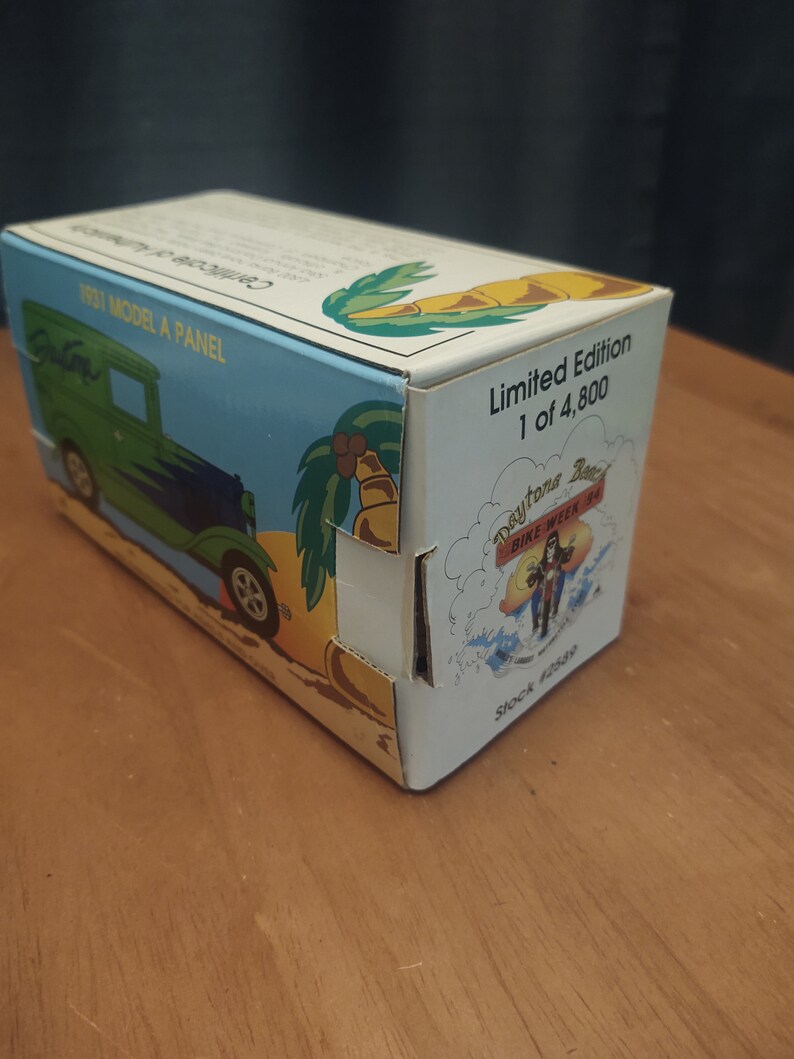 Puede incluir: Un coche de juguete azul y verde 1931 Model A Panel en una caja con una escena de playa y palmeras. La caja dice "Edici&oacute;n limitada 1 de 4.800" y "Daytona Beach Bike Week '94".