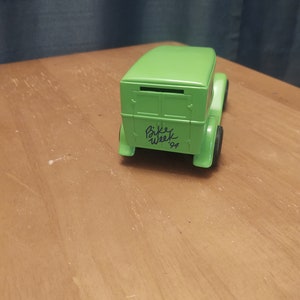 Puede incluir: Modelo de juguete verde de un cami&oacute;n de reparto vintage con una ranura en la parte trasera. El cami&oacute;n tiene escrito "Bike Week '94" en el lateral.