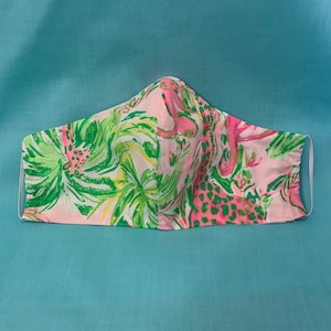 Puede incluir: Máscara facial rosa y verde con un diseño de estampado floral y animal.