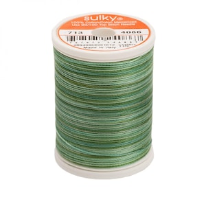 May include: A spool of Sulky brand thread, featuring a blend of green hues. The label indicates it's 100% cotton, mercerized, and suitable for a 90/100 top stitch needle. The spool has the numbers 713 and 4086 on the label.