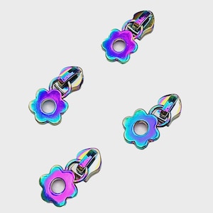 May include: Four iridescent rainbow zipper pulls with a flower design. Each pull has a metal ring and a small hole in the center of the flower.