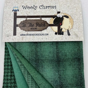 May include: Wooly Charms fabric bundle featuring four different green wool fabrics with a plaid, houndstooth, and solid pattern. The fabric is made by In The Patch Designs.