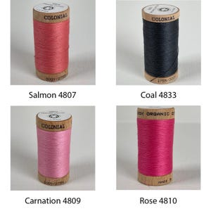 K&ouml;nnte beinhalten: Vier Garnrollen in verschiedenen Farben: Lachs, Kohle, Nelke und Rose. Jede Rolle ist mit "Colonial" beschriftet und hat eine L&auml;nge von 300 Yards oder 275 Metern.