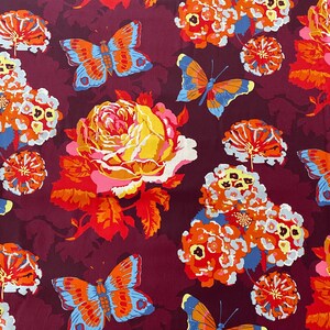 May include: A burgundy fabric with a repeating pattern of orange, yellow, and white flowers, and butterflies with blue, orange, and red wings.