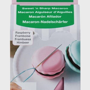 May include: A pink and green macaron-shaped needle sharpener with a needle threaded through it. The packaging includes the text "Sweet 'n Sharp Macaron" and "Clover" in green. The product is labeled as "1 pc."