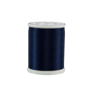 May include: A spool of navy blue thread. The thread is tightly wound around a white plastic spool. The top of the spool has a white label with blue text. The thread has a slight sheen.