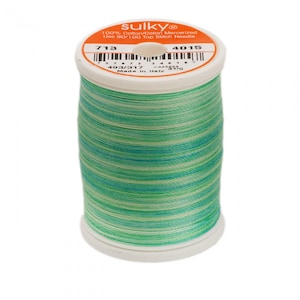 May include: A spool of Sulky brand thread, featuring a blend of green, blue, and white colors. The label indicates it is 100% cotton and mercerized. The spool is marked with the numbers 713 and 4015.