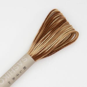 May include: A spool of brown, beige, and cream colored embroidery floss. The label reads "Sashiko" in Japanese characters and "刺し子" in English.